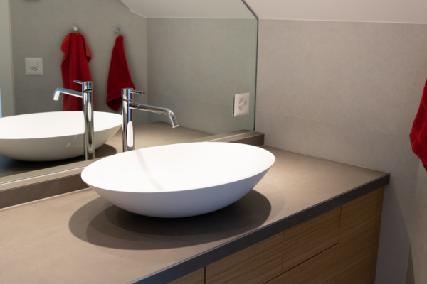 Lavabo de salle de bain rénovée à Lutry. Carrelage gris et mobilier en bois
