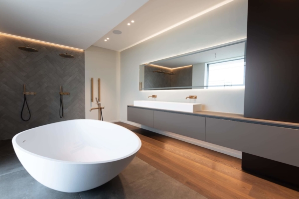 Salle de bains chic en carrelage gris et en bois. Lumière encastrée et mobilier design. Maison à Rolle