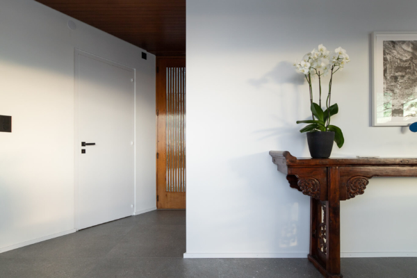Rénovation d'une villa d'architecte à Montreux. Carrelage gris dans une entrée avec porte en bois.