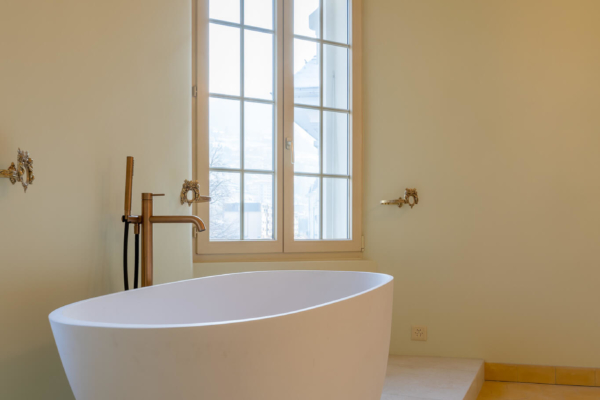 Baignoire dans chambre à coucher avec des murs vert pâle et fenêtre en fond