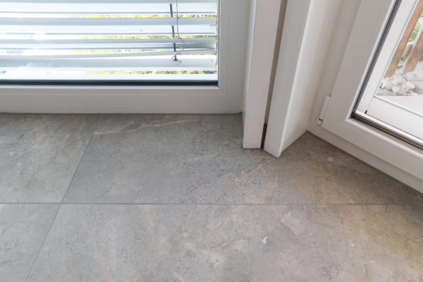 Détail d'ouverture de terrasse avec carrelage imitation pierre gris