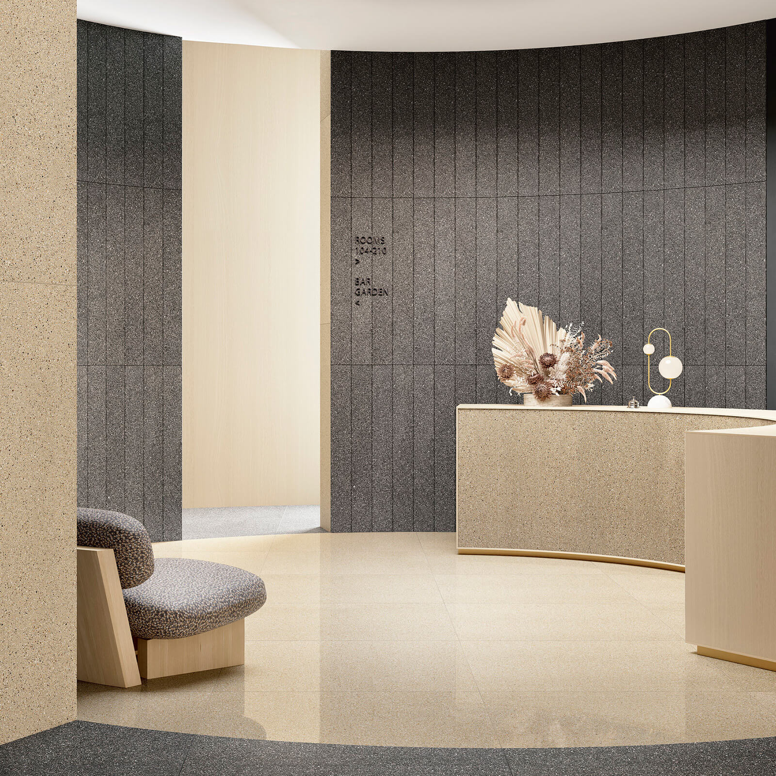 Il Veneziano 6 Zone de réception présentant un mélange de carreaux de mur foncés et clairs de la collection Il Veneziano, avec un bureau élégant beige et un fauteuil lounge rond en tissu à motifs.