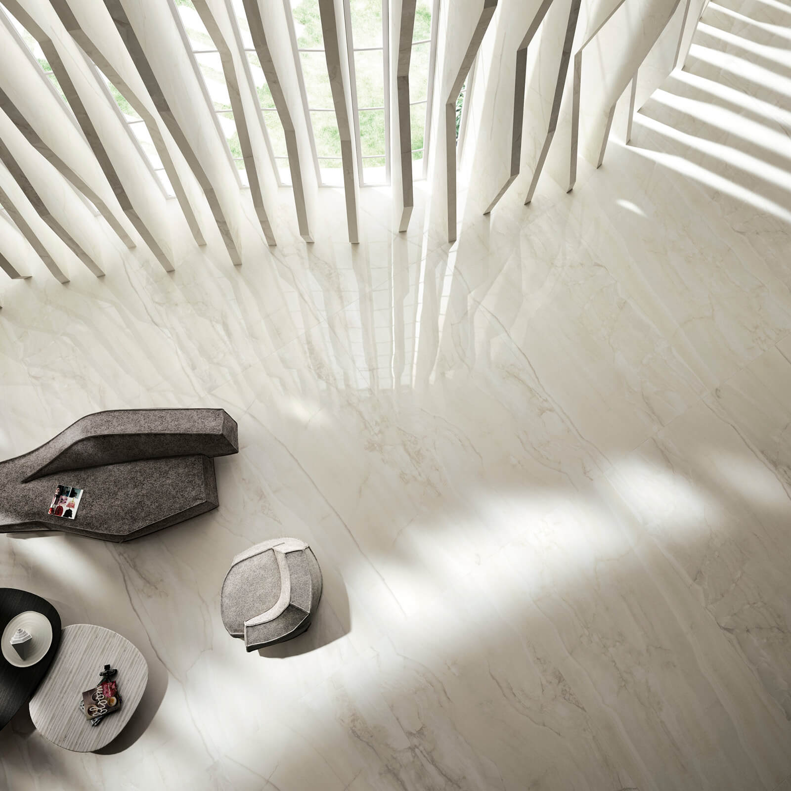Marmi Maximum Bright Onyx 2 Vue aérienne d'un hall lumineux avec sol en marbre Marmi Maximum Bright Onyx, meubles contemporains en tissu gris, entouré de colonnes en marbre blanc et de grandes fenêtres.