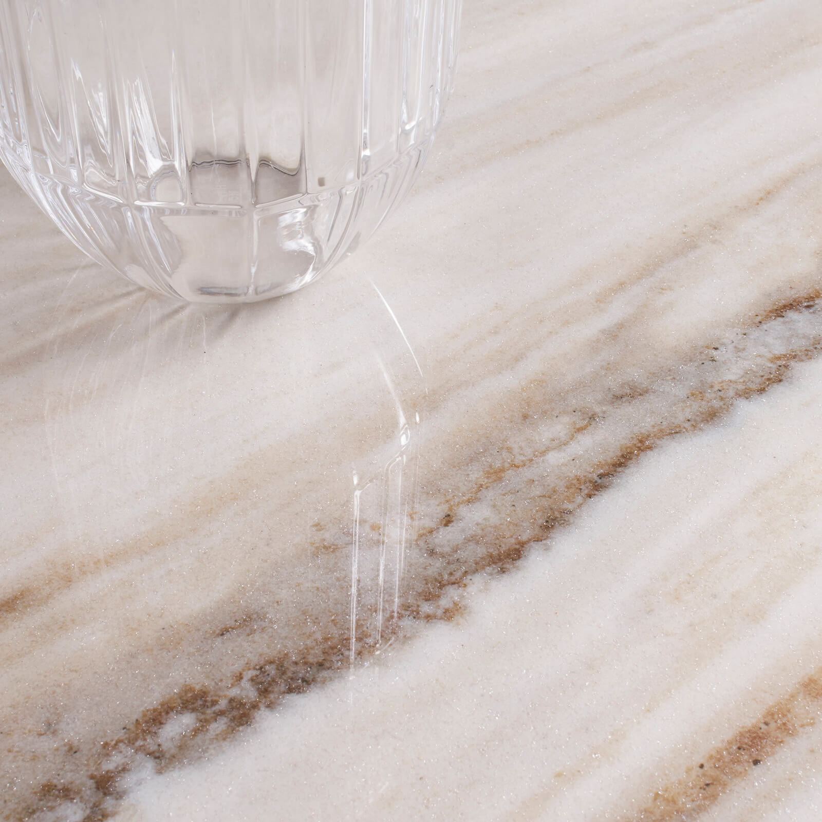 Marmi Maximum Palissandro White 2 Un gros plan sur un verre posé sur un carrelage imitation marbre Marmi Maximum Palissandro, capturant les détails exquis des veines et des nuances du marbre. L'éclairage met en valeur la texture et les couleurs subtiles du carrelage.