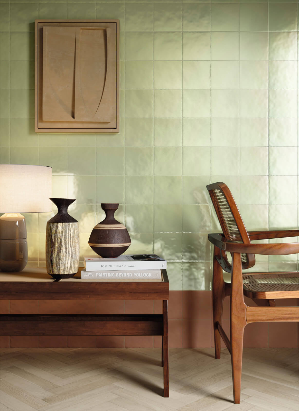 Bottega d'Arte TerreLustrate 4 coin salon avec des carreaux de faïence Bottega d'Arte TerreLustrate vert pâle et orange clair, chaise en bois avec assise en cannage, table basse en bois avec des livres et des vases décoratifs, lampe de table moderne.